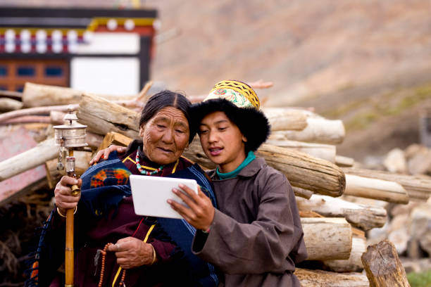 Young boy with grandmother using digital tablet Young boy with grandmother holding prayer wheel and looking at digital tablet lahaul and spiti district photos stock pictures, royalty-free photos & images