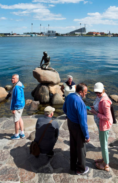turisti alla statua della sirenetta nel porto di copenaghen - denmark danish culture copenhagen sculpture foto e immagini stock