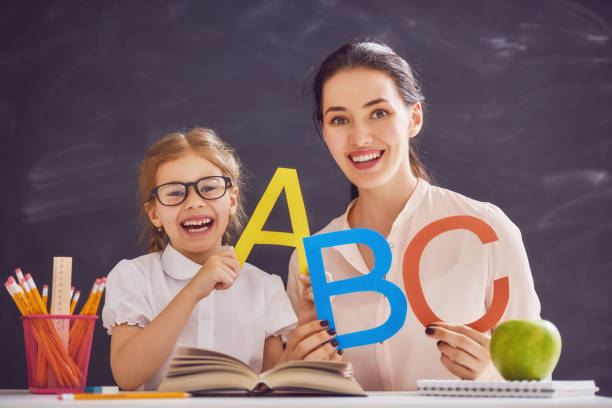 madre e figlia stanno imparando a scrivere - reading and writing classroom alphabet learning foto e immagini stock