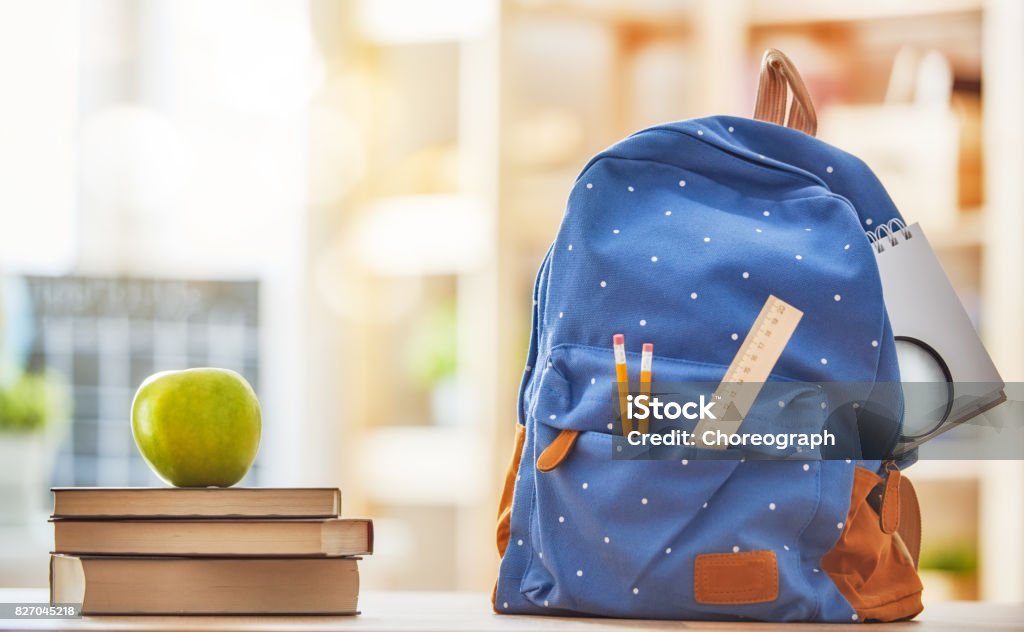 Apple, pile of books and pencils Back to school and happy time! Apple, pile of books and backpack on the desk at the elementary school. Backpack Stock Photo