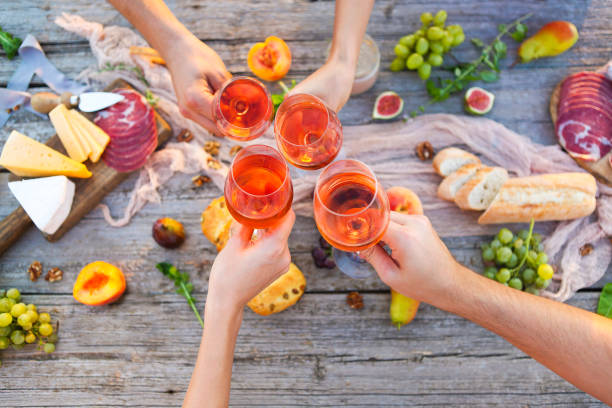 giovani che fanno brindisi al picnic con vino rosato - beach table peach fruit foto e immagini stock
