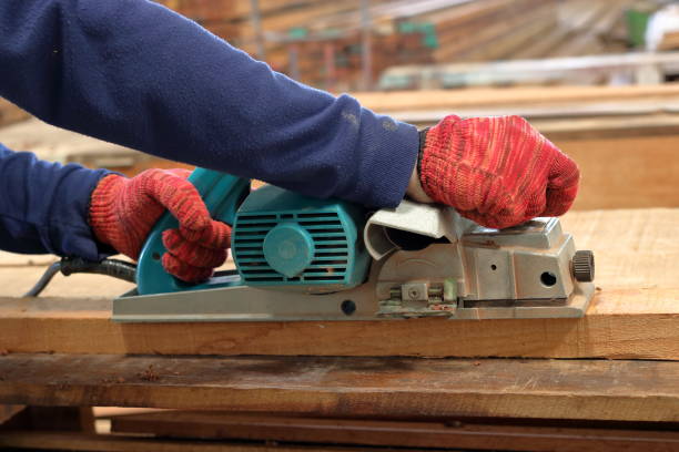 istock Hand of carpenter using electric planer with wooden plank in carpentry workshop 827055210