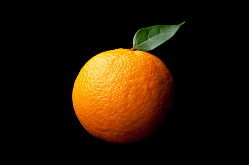 Orange with leaf against a black background