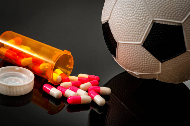 Doping in football Doping in sports and steroid abuse concept with a soccer ball, a bottle of prescription pills on a dark background anti doping stock pictures, royalty-free photos & images
