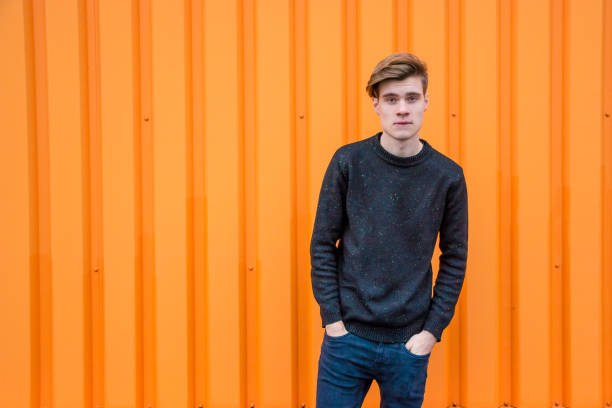 istock Teenage boy standing over contrasting orange background with copyspace 827078090