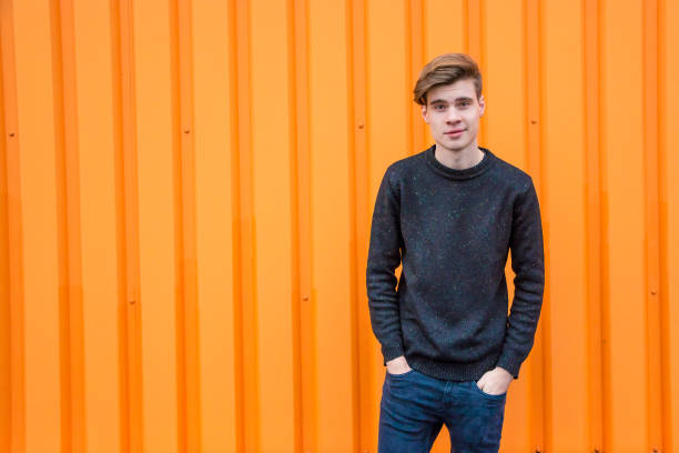 istock Teenage boy standing over contrasting orange background with copyspace 827078094