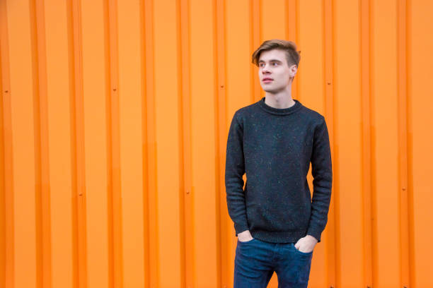 istock Teenage boy standing over contrasting orange background with copyspace 827078190