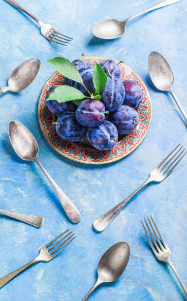 istock Plums group with leaves on plate with forks and spoons 827078336