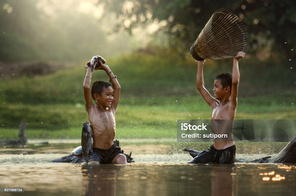 Asia Two boys joyful catch fish in the lake Asia Two boys joyful catch fish in the lake this is the lifestyle of children in Countryside Thailand. Child Stock Photo
