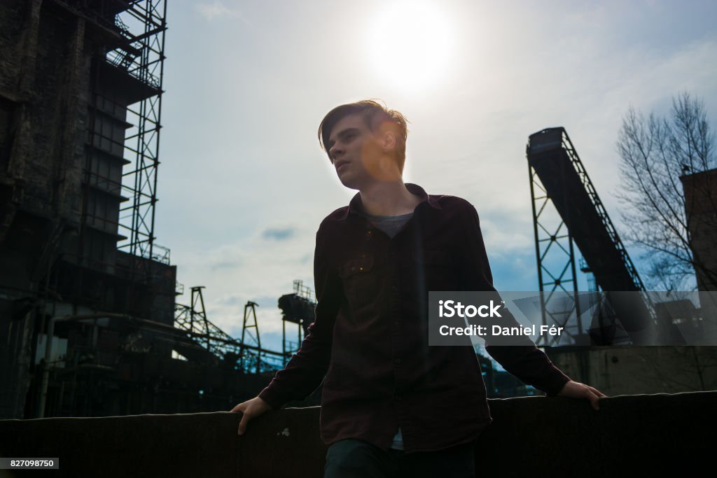 Teenage boy in industrial area Teen boy with industrial area mine silhouettes dark place near town Abandoned Stock Photo