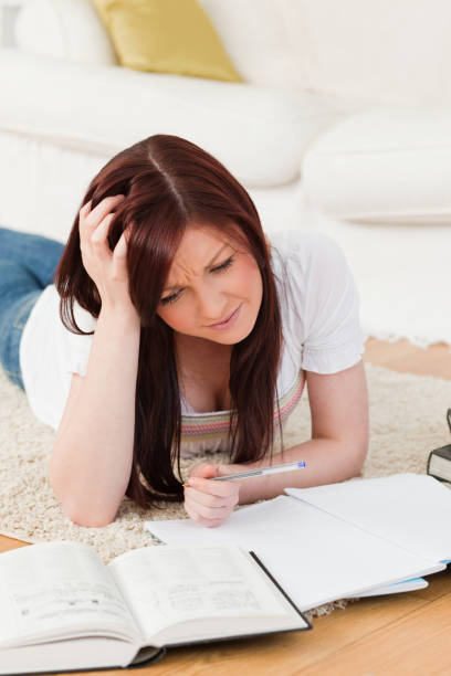 istock Pretty redhaired girl studying for while lying on a carpet 827099784