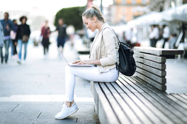 istock Woman using laptop on the street 827144898