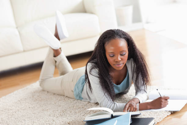 istock Woman lying on carpet doing a book review 827144910
