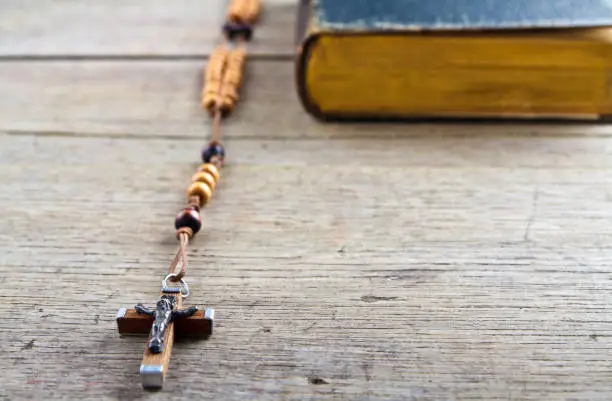 The book of Catholic Church liturgy and rosary beads on the wooden table