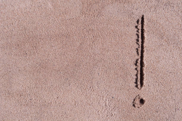 Handwritten exclamation mark on brown sand on the beach in sunny day