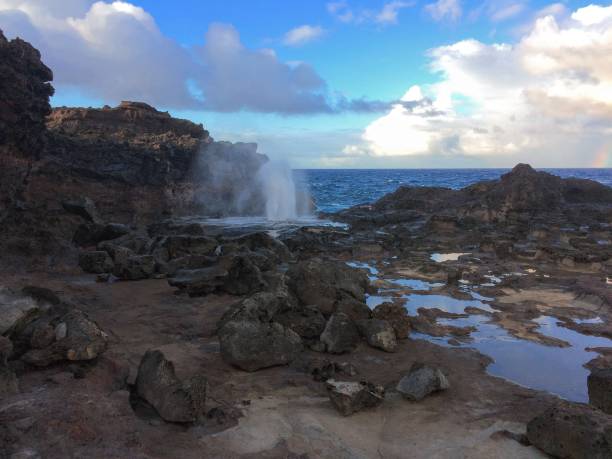 istock Nakalele Blowhole with water spraying out that was created from Pacific Ocean waves hitting the tall rocky cliff coastline that was created from lava on Maui, Hawaii, USA sky reflecting off the still water 827148160