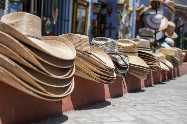 Hats for sale on a curb in Todos Santos, Baja Sur, Mexico A row of hats for sale on a red curb in Todos Santos, southern Baja California, Mexico, Cabo San Lucas area. tienda stock pictures, royalty-free photos & images