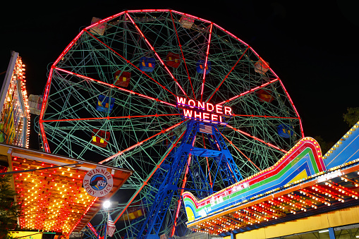 Colorful lights at a funfair in Münster, Germany and some cars passing by in the foreground.