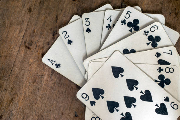 istock Spread white playing cards with black symbols on a wooden table surface 827164034