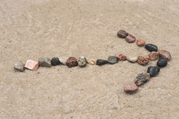 istock pebble arrow sign on sand 827177382
