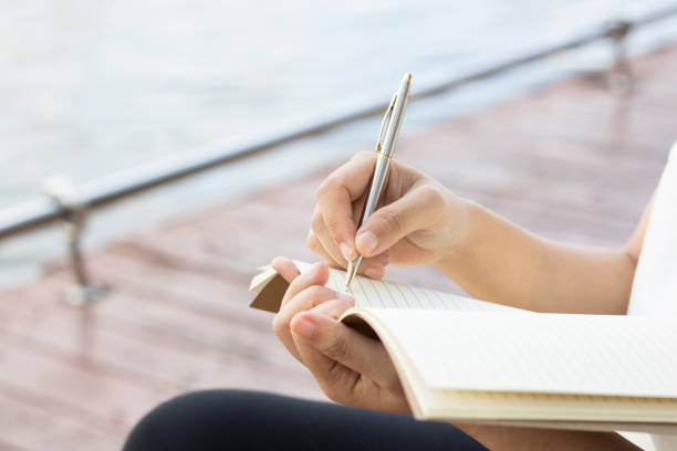 istock Writing dairy on notebook in park, concept as memory of life and education 827180928