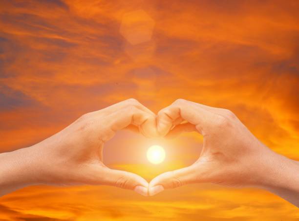 istock hand forming  a heart shape with  sunset  light and copy space for add text 827191100