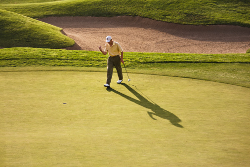 Player preparing to shoot on the golf course at sunset.