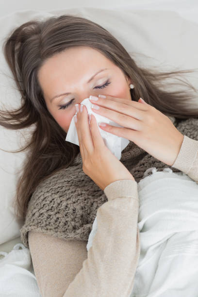 istock Woman lying on sofa and blowing nose 827197454