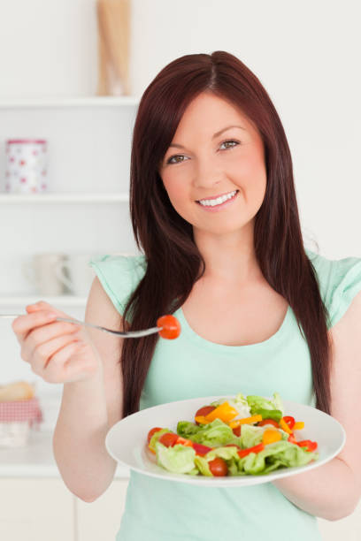 istock Good looking redhaired woman enjoying a mixed salad in the kitchen 827197910