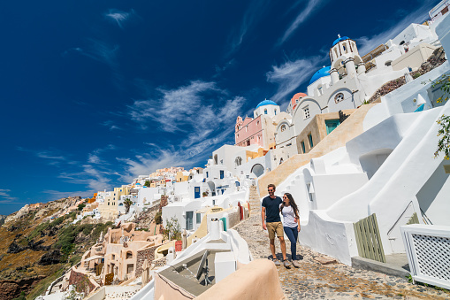 amazing architecture of oia village of santorini greek island with blue sky and young tourist couple walking