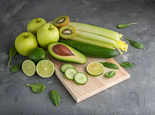 A set of fresh,green fruits and vegetables on a grey concrete background.Top view.