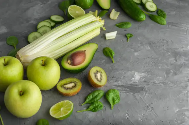 A set of fresh,green fruits and vegetables on a grey concrete background.Close-up.