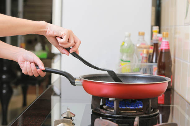 istock Woman holding a pan in the hand cooking in kitchen. 827211992