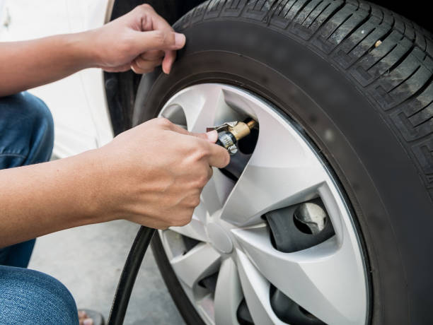 man filling air pressure in the car tyre - inflating imagens e fotografias de stock