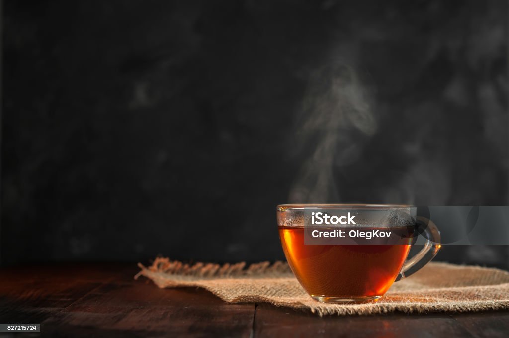 A Cup of freshly brewed black tea,escaping steam,warm soft light, darker background. Tea - Hot Drink Stock Photo