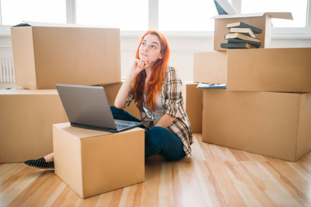 istock Girl using laptop among cardboard boxes, new house 827218606