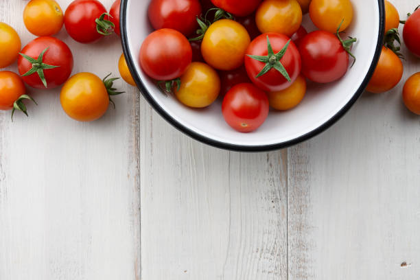 istock Red and yellow cherry tomatoes on white wooden table 827218720