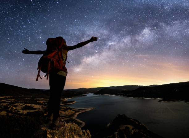 istock Silhouette of a female backpacker enjoying the view under miky way 827220146