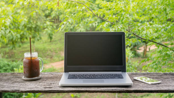 istock Laptop and iced americano coffee on a wooden table. 827231596