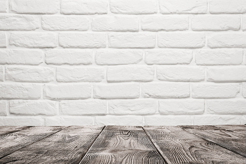 Empty wooden table over white brick wall background with copy space