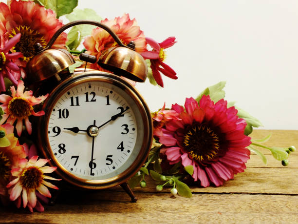 istock spring time with alarm clock and artificial flowers bouquet background 827252056