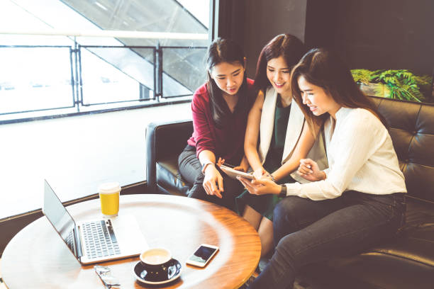 istock Three beautiful Asian girls using smartphone and laptop, chatting on sofa at cafe, modern lifestyle with gadget technology or working woman on casual business concept 827261814