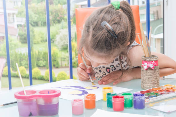 istock Girl draws paints by the window.Learning to draw. 827267352