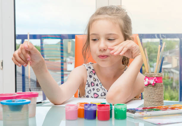 istock Girl draws paints by the window.Learning to draw. 827269214