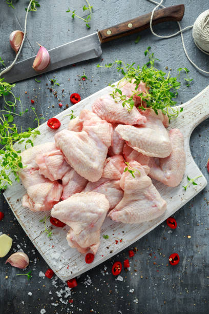 istock Fresh raw chicken wings on a white cutting board with thyme, chilli, salt, pepper, garlic 827276210
