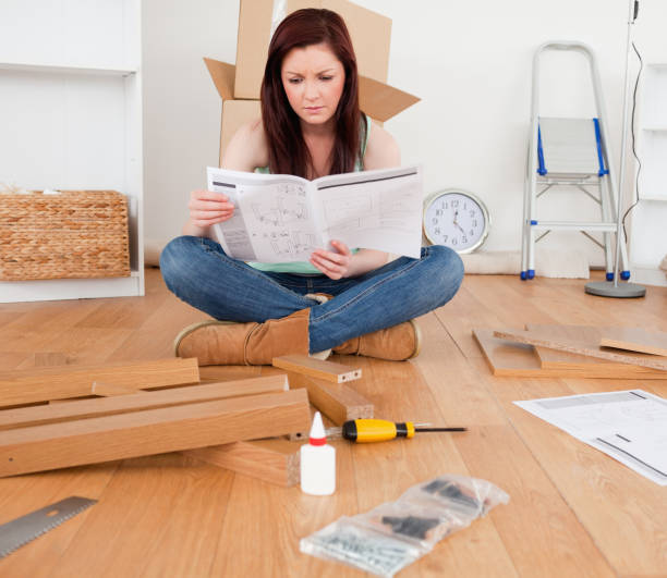 istock Beautiful redhaired woman reading a manual before do-it-yourself 827279622