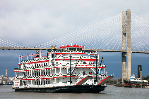 Savannah, Georgia, USA - December 29, 2016: Riverboat Georgia Queen on tour. Talmadge Memorial Bridge and commercial port in background.