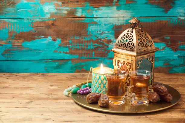 istock Lightened lantern, tea cups and dates on wooden table over rustic background. Ramadan kareem holiday celebration concept 827284388