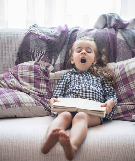 istock little girl reading book on sofa 827287358