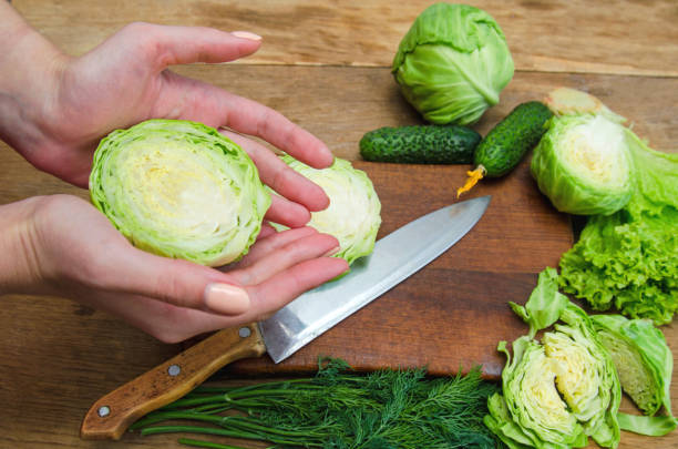 istock Female hands cutting fresh cabbage on a wooden cutting board 827288610